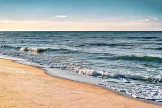 Le rivage d'une plage antillaise par temps calme Plage de sable clair et vagues venant se briser sur le rivage